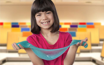Girl in pink shirt smiling holding blue slime with both hands 